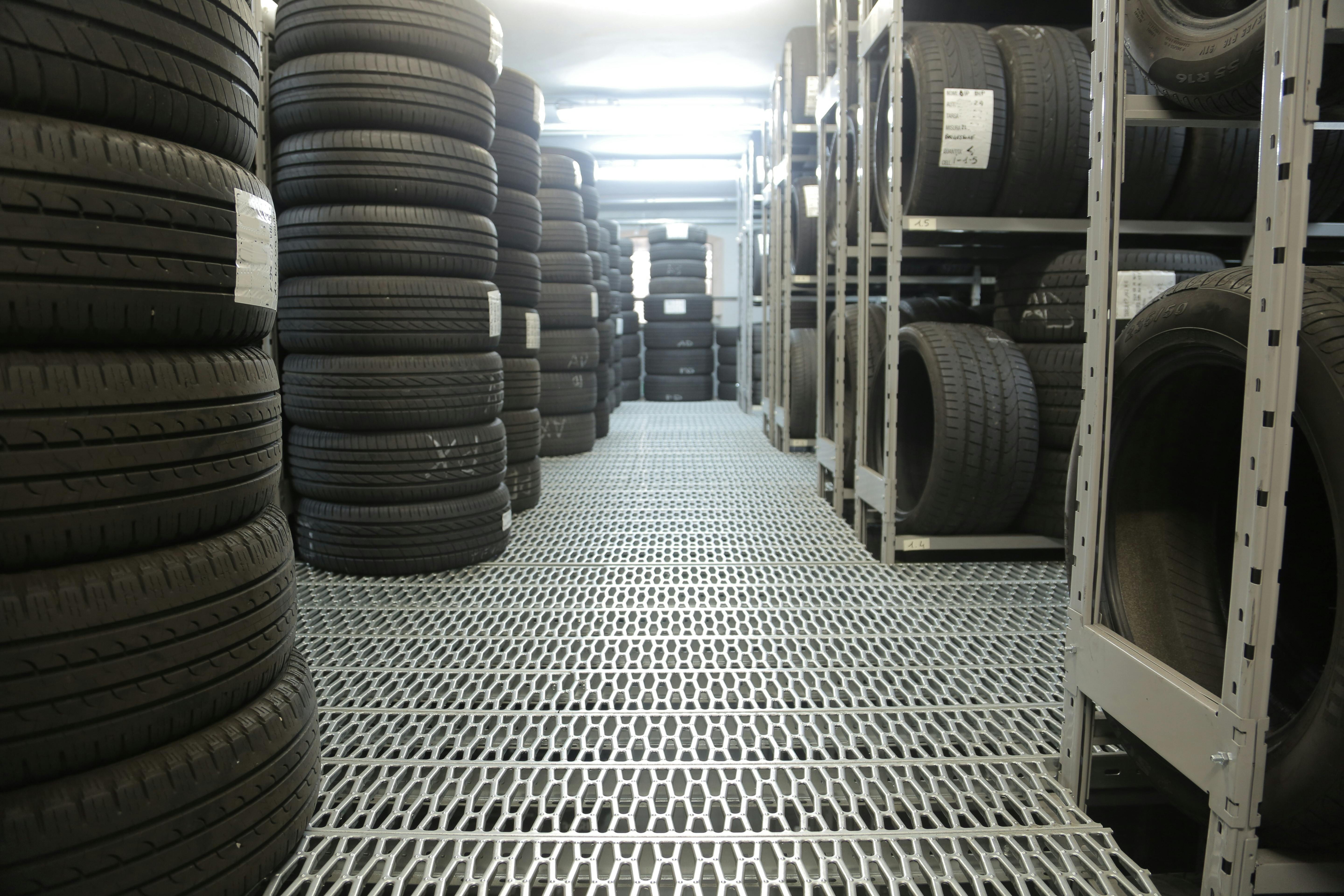 Rows of stacked tires in an indoor industrial warehouse for storage.