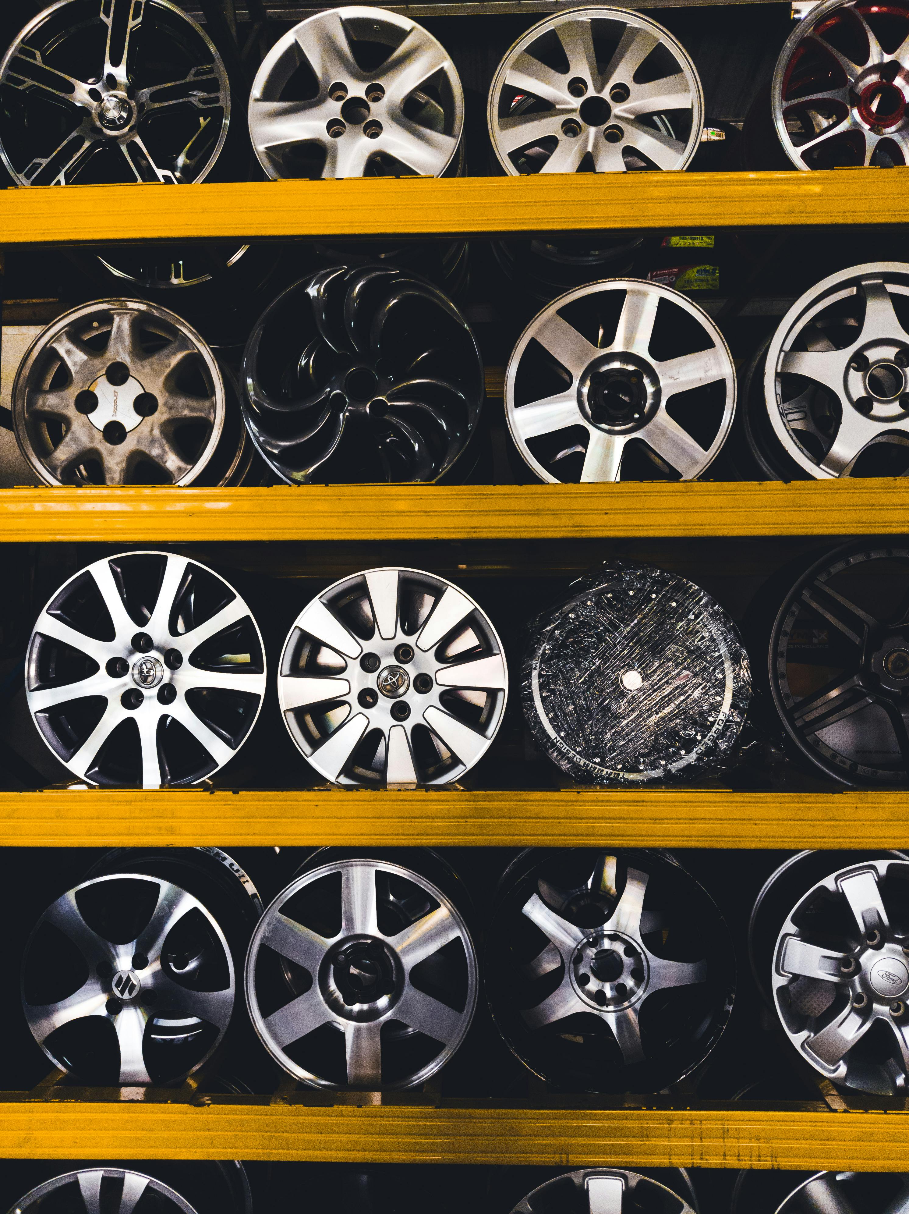 Vertical shot of various car rims displayed on shelves in Malaysia, showcasing different designs.